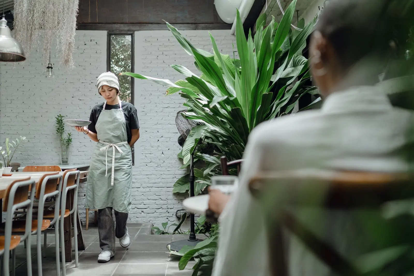 Cafe server in a sage apron carrying a plate