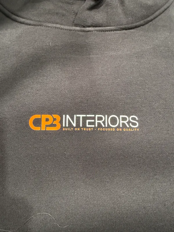 Dark grey hoodie with a small CPB Interiors logo printed on the chest