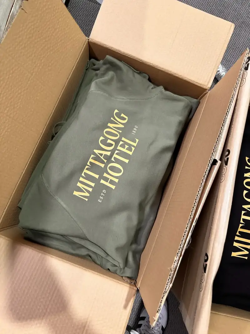 Green hoodie with a printed logo packed in a box
