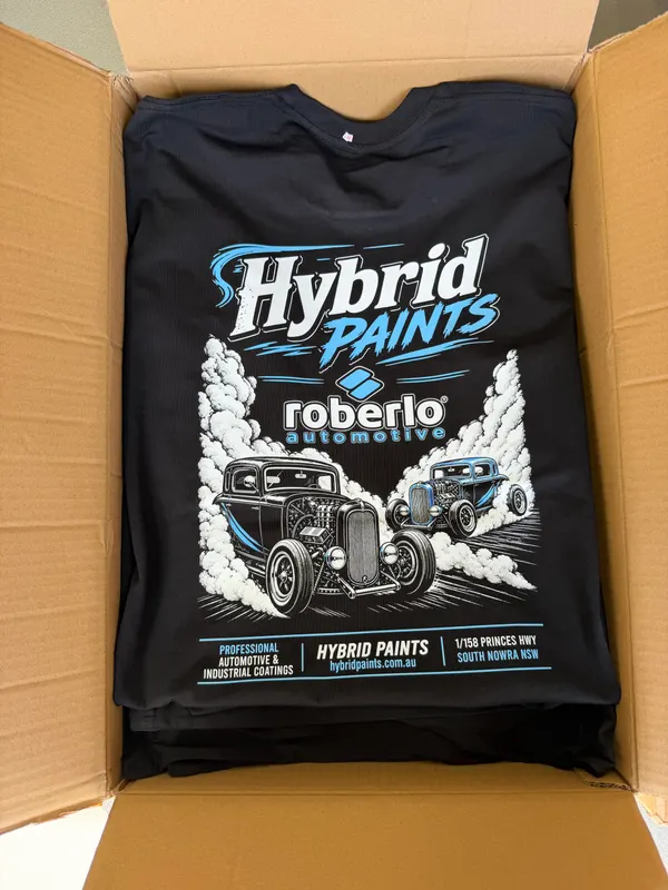 Box of black tees printed with a Hybrid Paints and Roberlo Automotive graphic of two hot rods