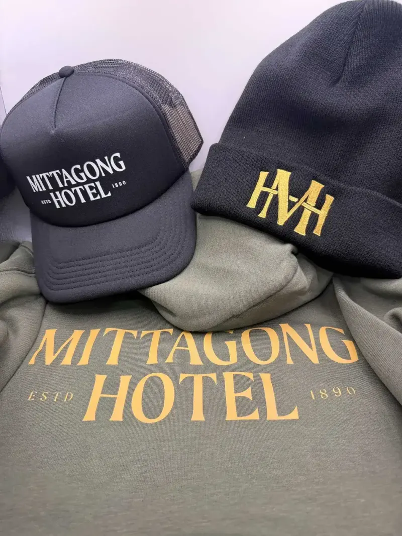 Mittagong Hotel merchandise: charcoal trucker cap, gold-embroidered black beanie and olive hoodie with a gold print