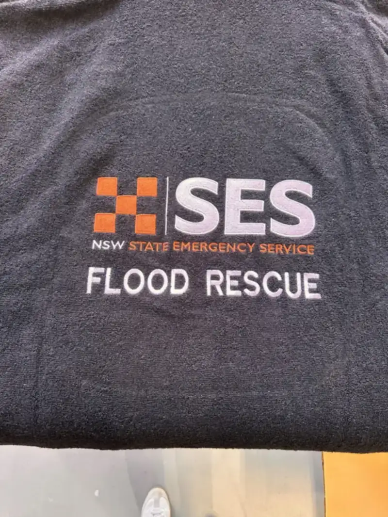 Grey tee printed with a flood rescue crest
