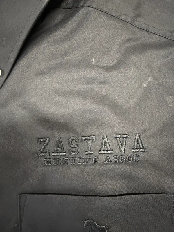 Black work shirt with black-on-black embroidery reading Zastava Hunting Assoc. above the pocket
